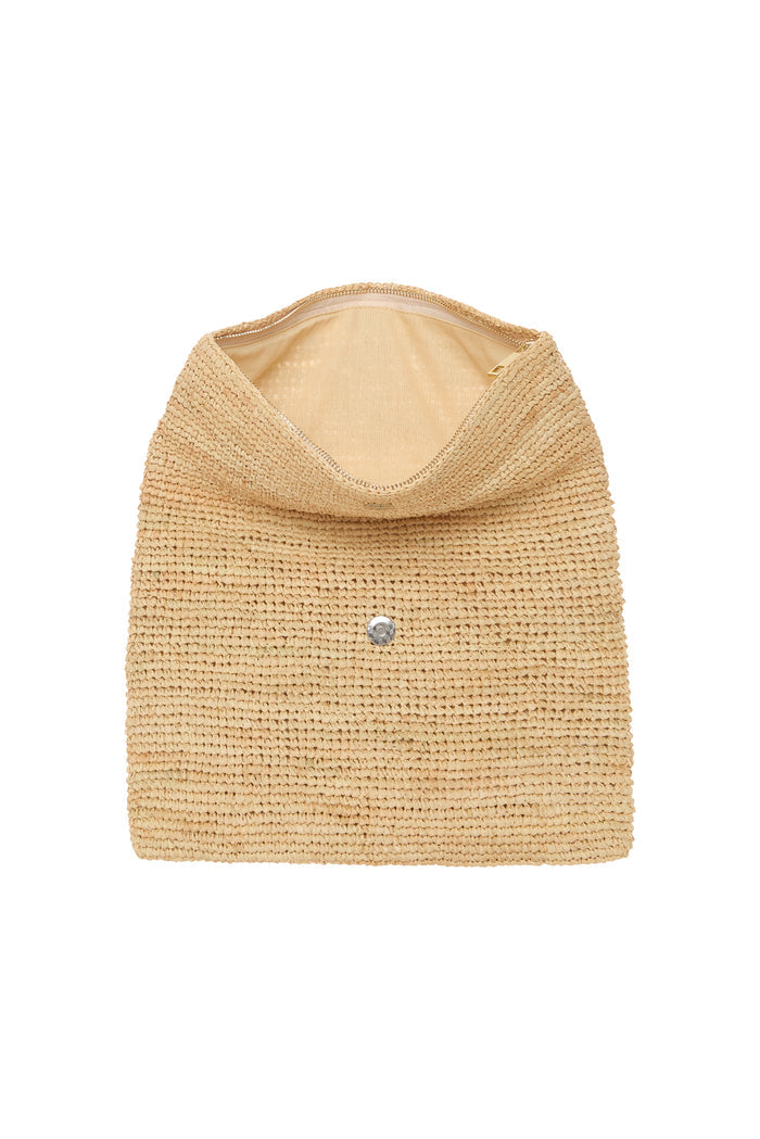 Top view of Cannes Clutch showing open interior, tan woven raffia exterior, fold-over flap with visible zipper on white background