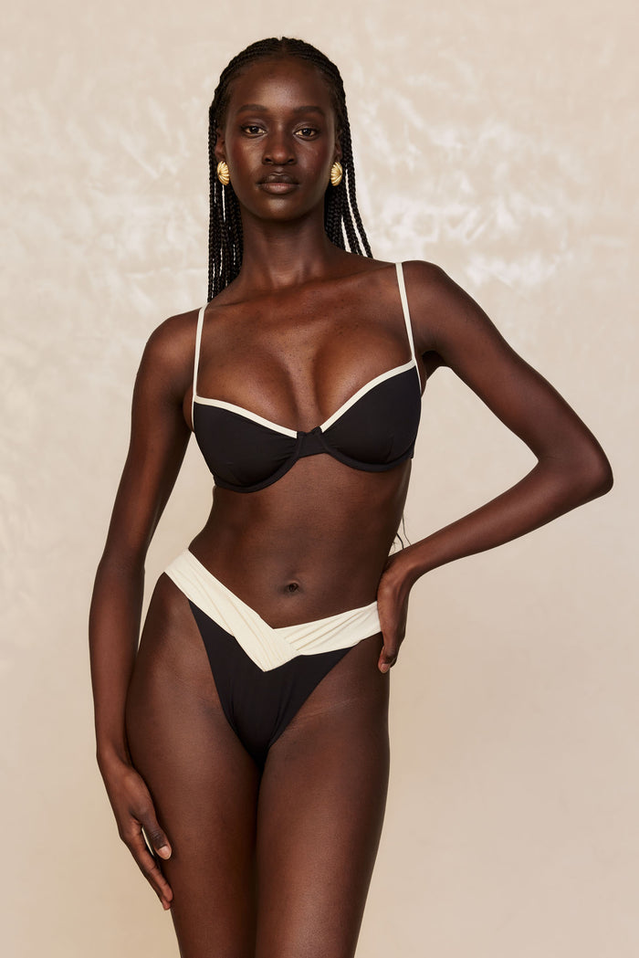 Front view of Marseille Bottom in Black/Ivory showcasing crossed ivory V-waistband and high-leg, high-rise cut on beige backdrop