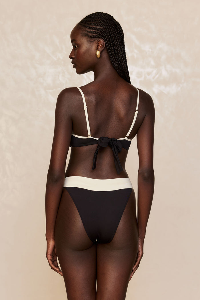 Rear view of Marseille Bottom in black and ivory, high-cut with contrast ivory waistband on model against a neutral beige background