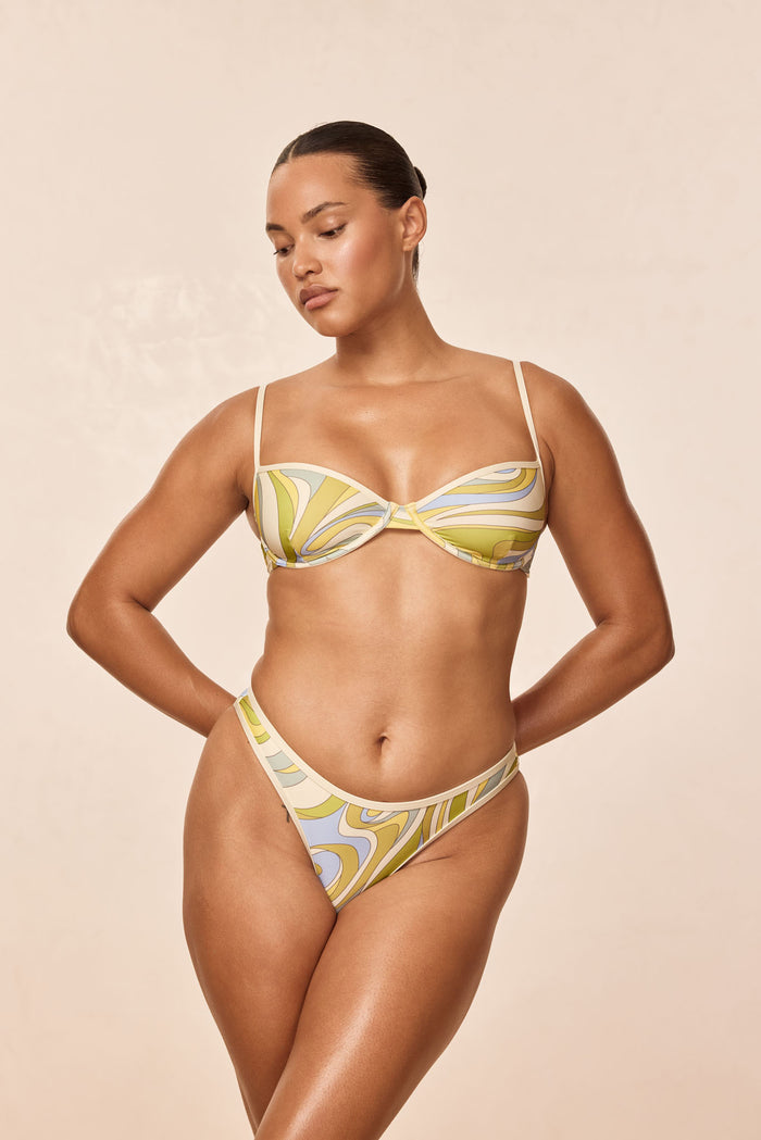 Front view of Capri Top in Costa Rei Apple and Ivory, underwire balconette with thin straps on beige background