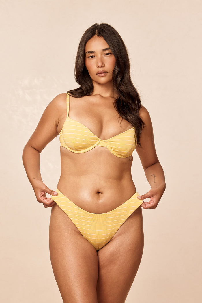 Front view of Capri Top - Meyer Stripe showing underwire cups, adjustable straps and gold back-tie on a model against a beige background