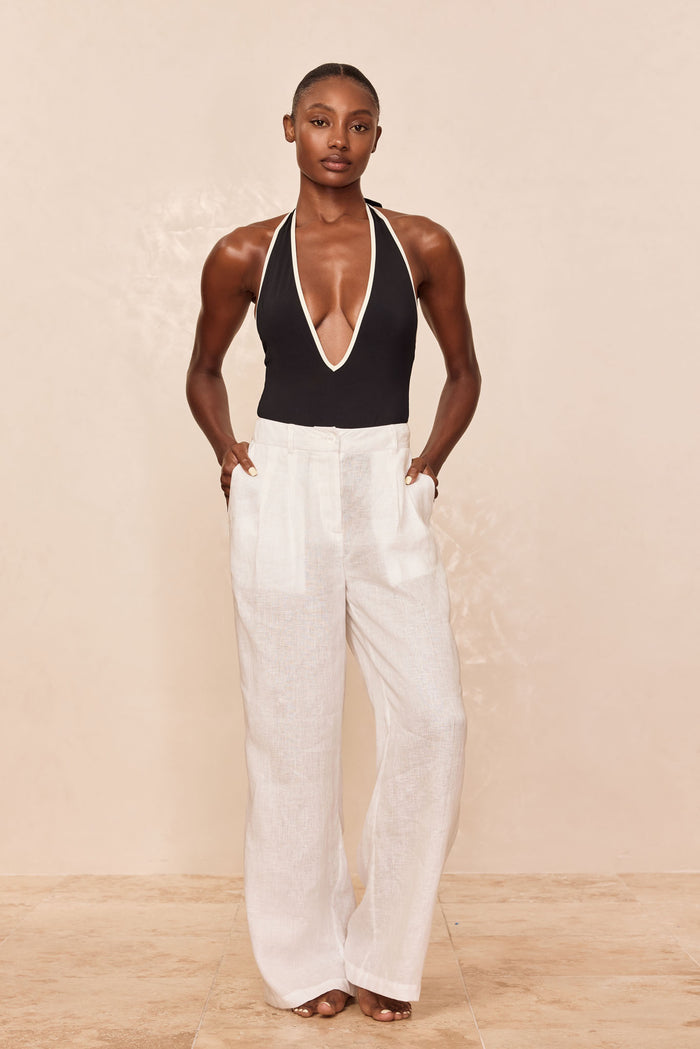 Front view of Casablanca Pants in white linen, wide leg high-rise with front pleats and pockets against beige backdrop