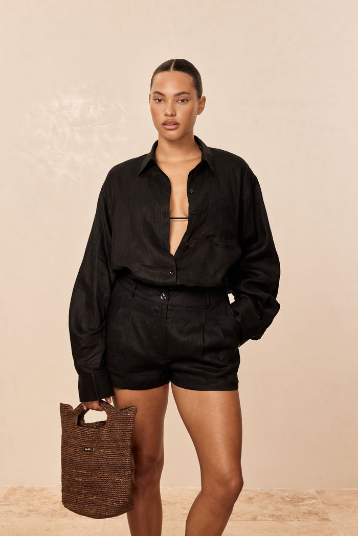 Front view of Casablanca Short, black linen, on model with high-waist tailored fit, front pleats and side pockets on beige background