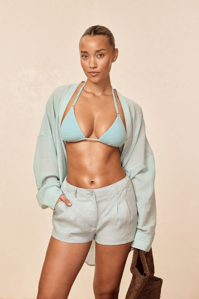 Front view of Casablanca Short in Light Slate linen showcasing high-rise relaxed fit and button-front waist against beige background
