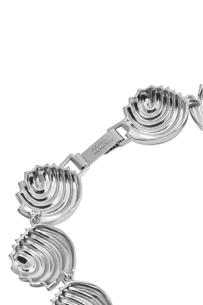 Close-up of Cayman Necklace in silver showing linked scallop-shell segments and engraved MONDAY clasp on white background