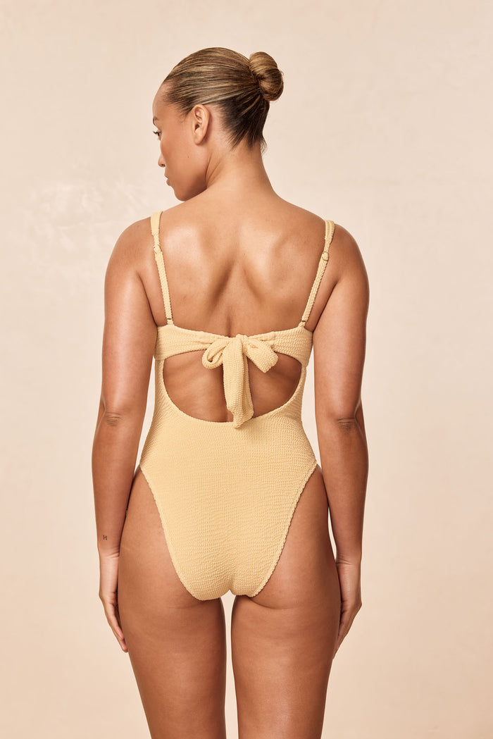 Back view of Clovelly One Piece in Raffia Crinkle showing tied open back, adjustable straps, and high-leg cheeky fit
