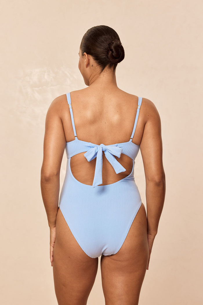 Back view of Clovelly one-piece in Sky Rib with ribbed fabric, tie-back cutout and adjustable straps on neutral background