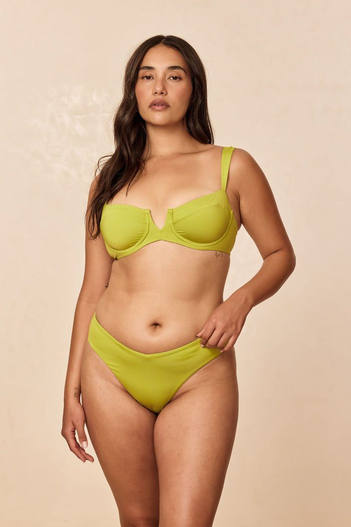 Front view of Clovelly Top in Apple showcasing underwire V-plunge balconette shape and wide straps on beige background