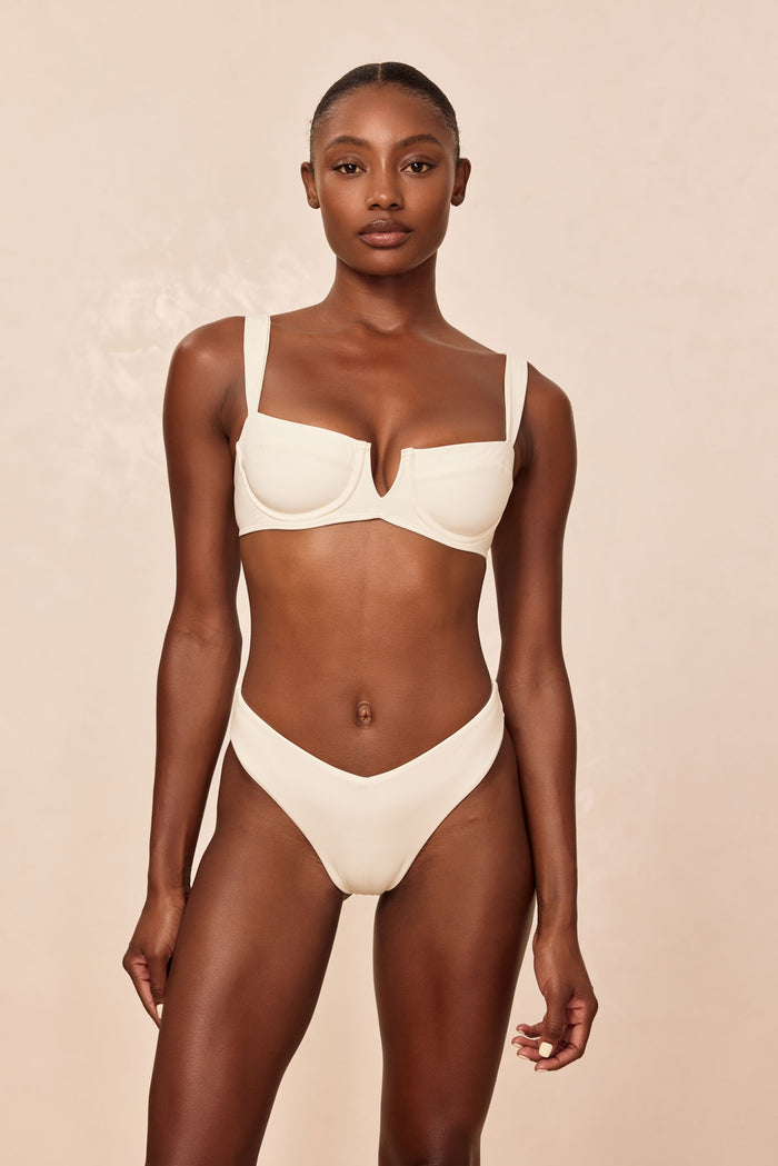 Front view of St Lucia Bottom in ivory on model showcasing V-front high-leg mid-rise fit on neutral beige background