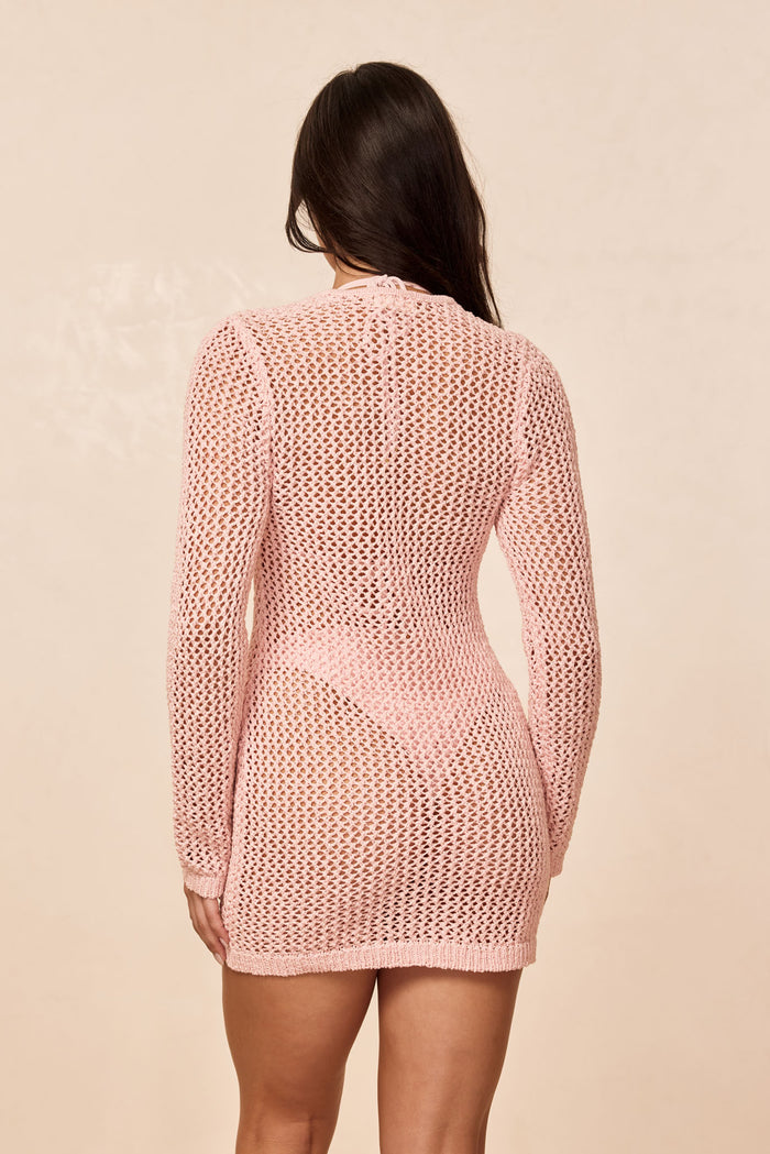 Back view of Corossol Mini Dress in powder pink, petit crochet open-knit with long sleeves, neutral beige background