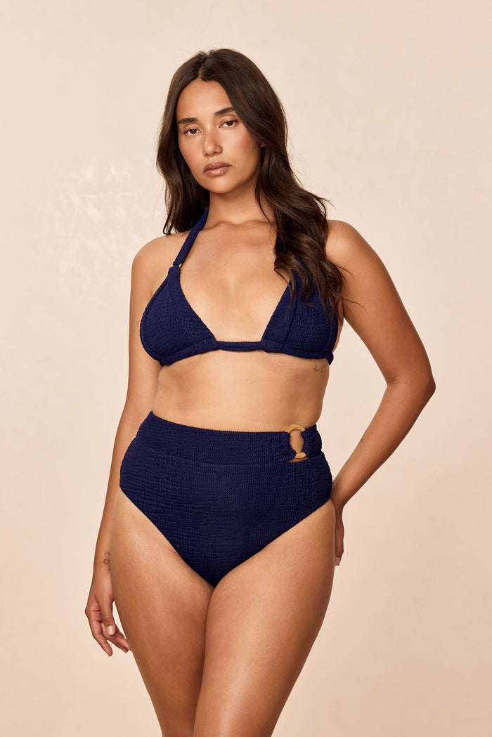 Front view of Costa Rica bottom in Midnight Crinkle, high-waist with crinkle texture and gold side ring on beige background