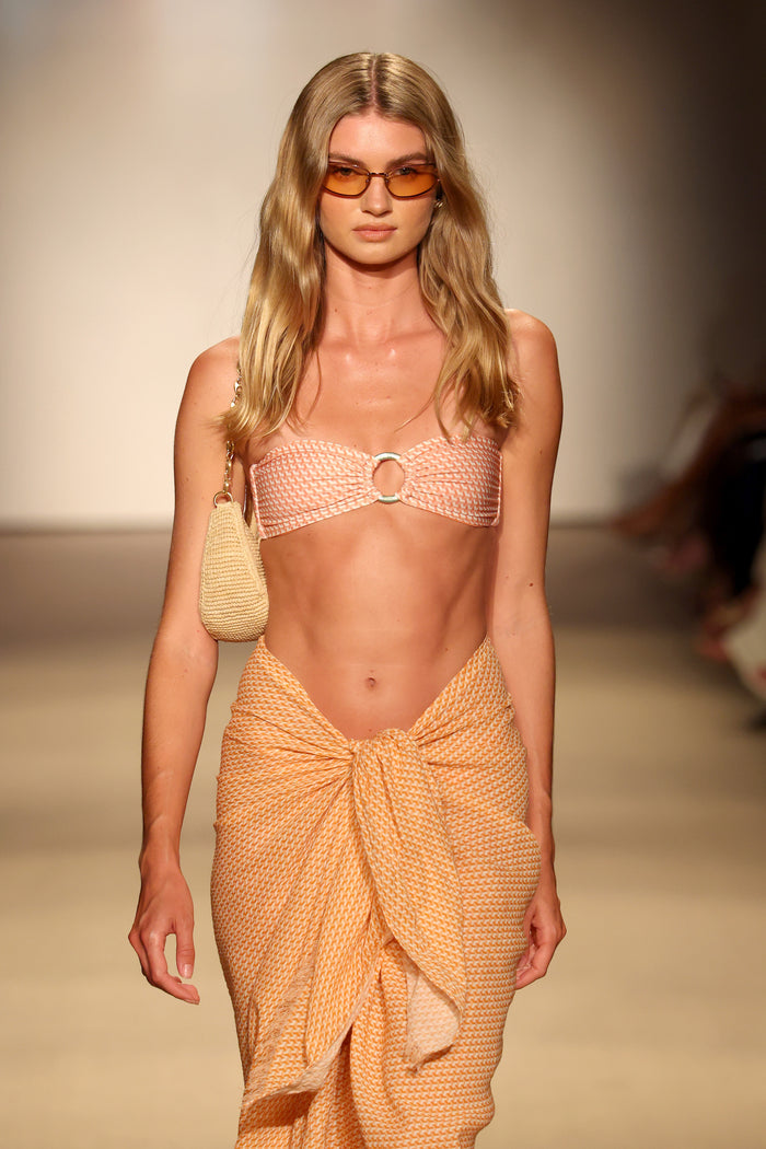 Front view of Costa Rica Top Micro Geo bandeau, peach micro-geo print with center metal ring on neutral runway