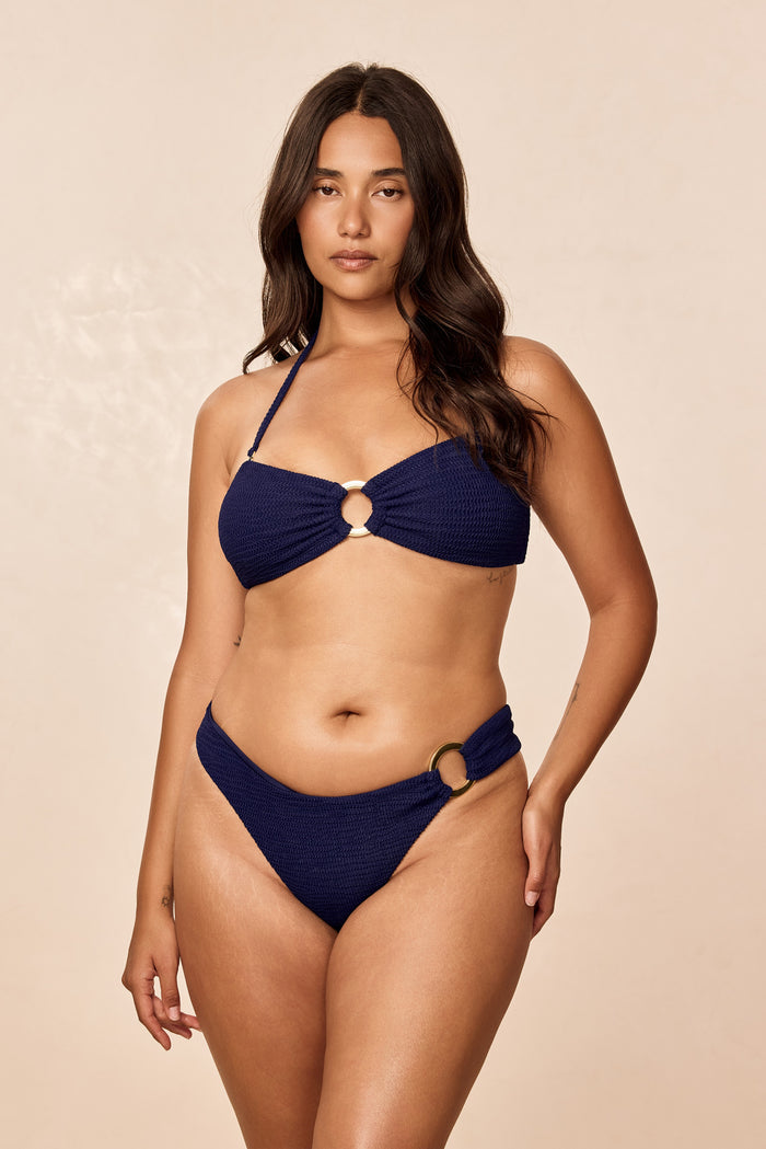 Front view of Costa Rica Top Midnight Crinkle showcasing navy crochet bandeau style with gold center ring and braided halter on model