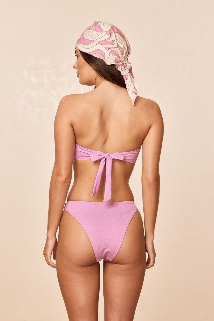 Back view of Costa Rica Top in Moonlight showing bandeau with adjustable back tie closure on model against beige background