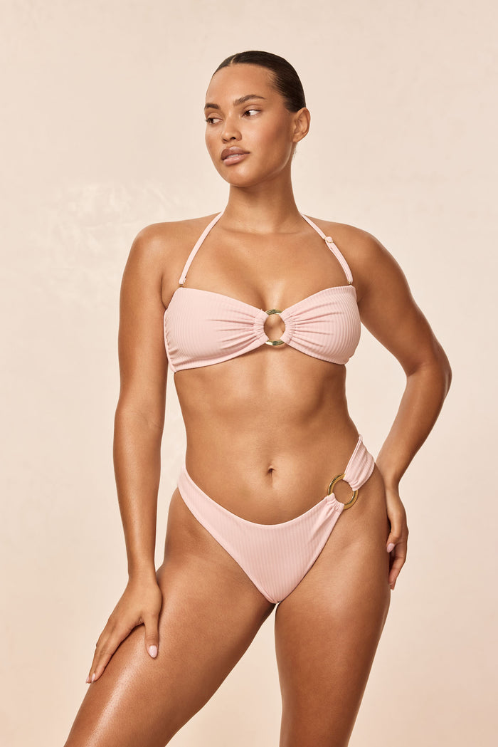 Front view of Costa Rica top in powder pink rib showcasing center gold ring and removable halter strap on neutral beige background