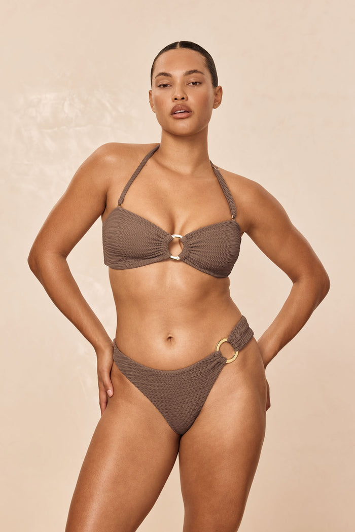 Front view of Bronte Bottom in Stone Crinkle on model, high-cut cheeky fit with textured fabric and gold ring hip detail