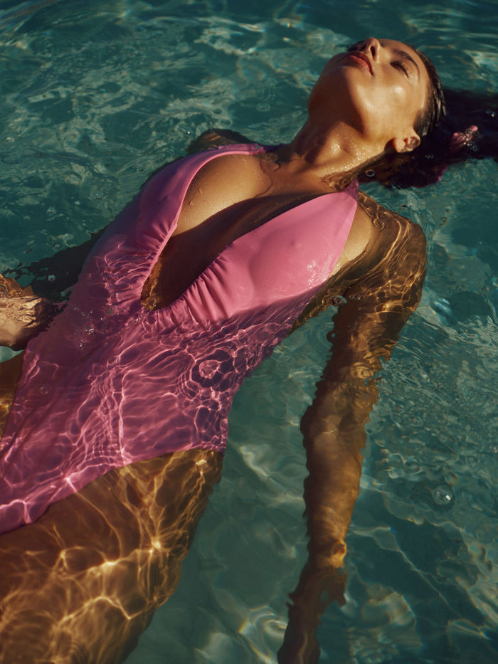 Close up of Croatia One Piece in Moonlight showing halter plunge and high cut leg with model floating in pool water