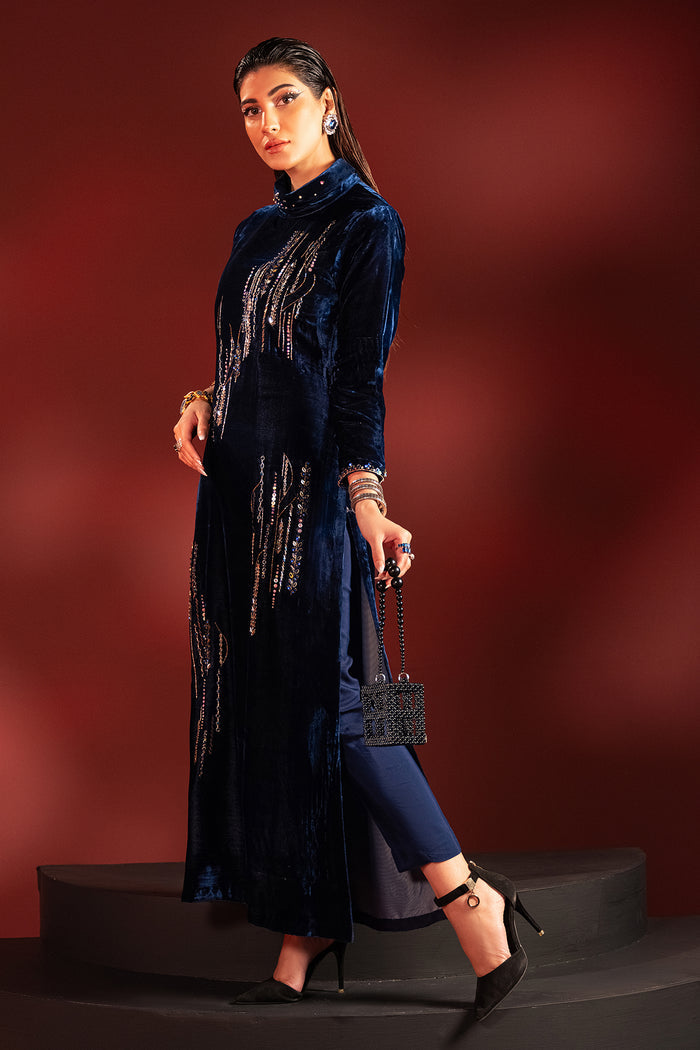 Walking pose of neon blue velvet formal dress highlighting straight silhouette and hand embellished neckline, ready to wear evening wear.