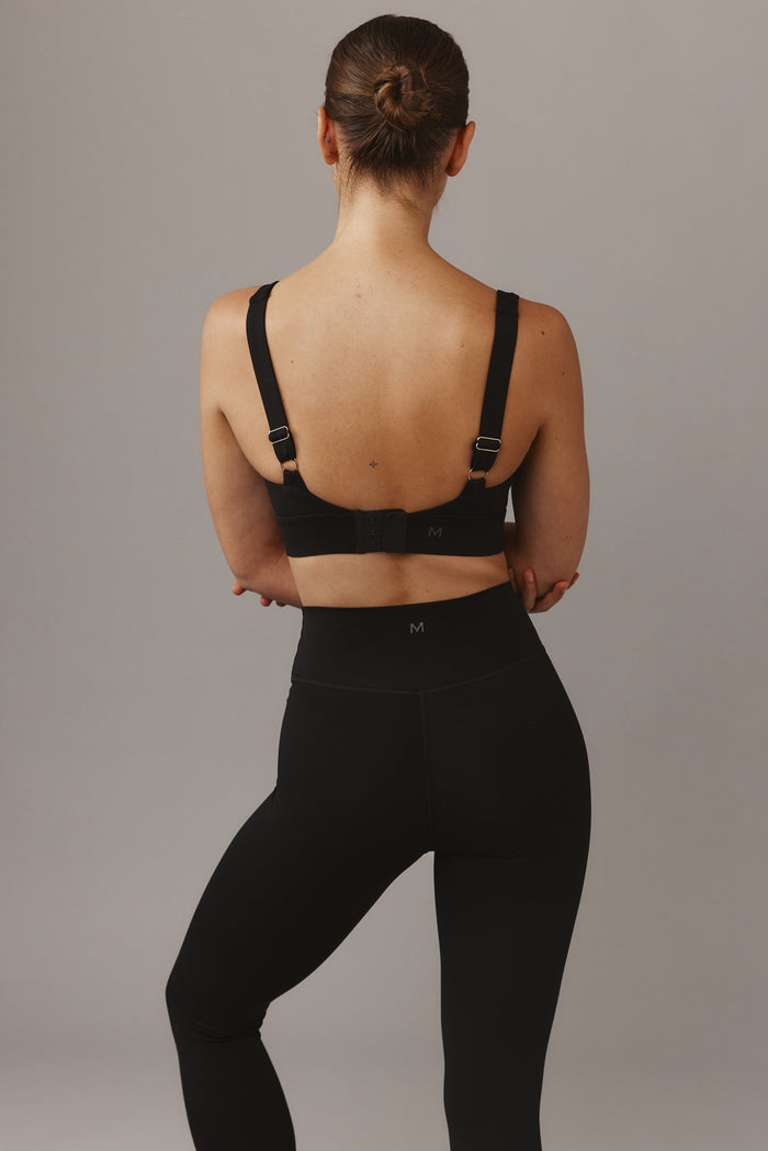 Rear view of Devin Bra in black showing adjustable straps, hook closure and elastic underband against gray backdrop