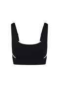 Black cropped sports bra with wide straps, white side piping, and small gold ring hardware.