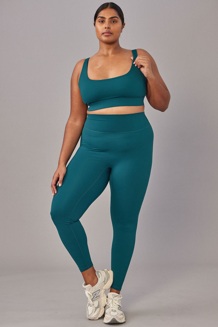 Front view of Devin Bra in Evergreen on plus-size model, scoop neckline and wide supportive straps, gray background