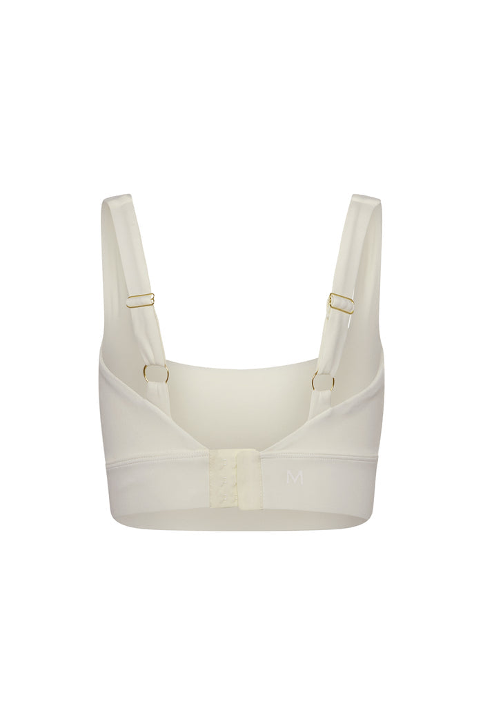 Cream wireless bra back view with adjustable straps, three-column hook-and-eye closure, size letter M on band.