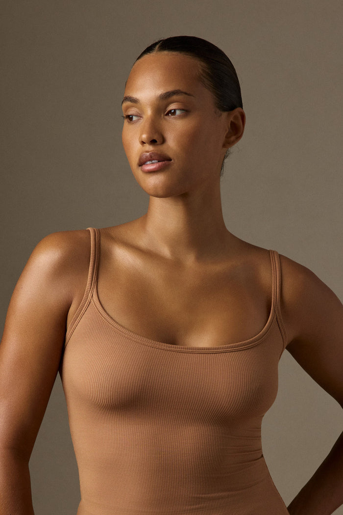 Three-quarter view of Devin Tank Long in caramel lightweight rib showing scoop neckline and fitted rib on model, neutral backdrop