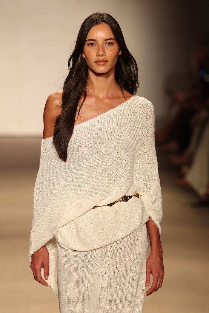 Front view of Dominica Poncho Open Knit in ivory on model showing off-shoulder open-knit texture, relaxed drape, and gold chain belt