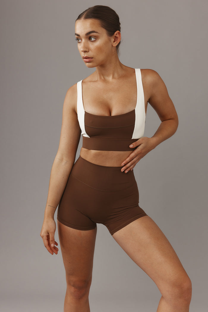 Three-quarter front of Elysian Short 4.5 inch in Cliffside showcasing high-waist fitted shorts paired with matching brown crop top on gray background