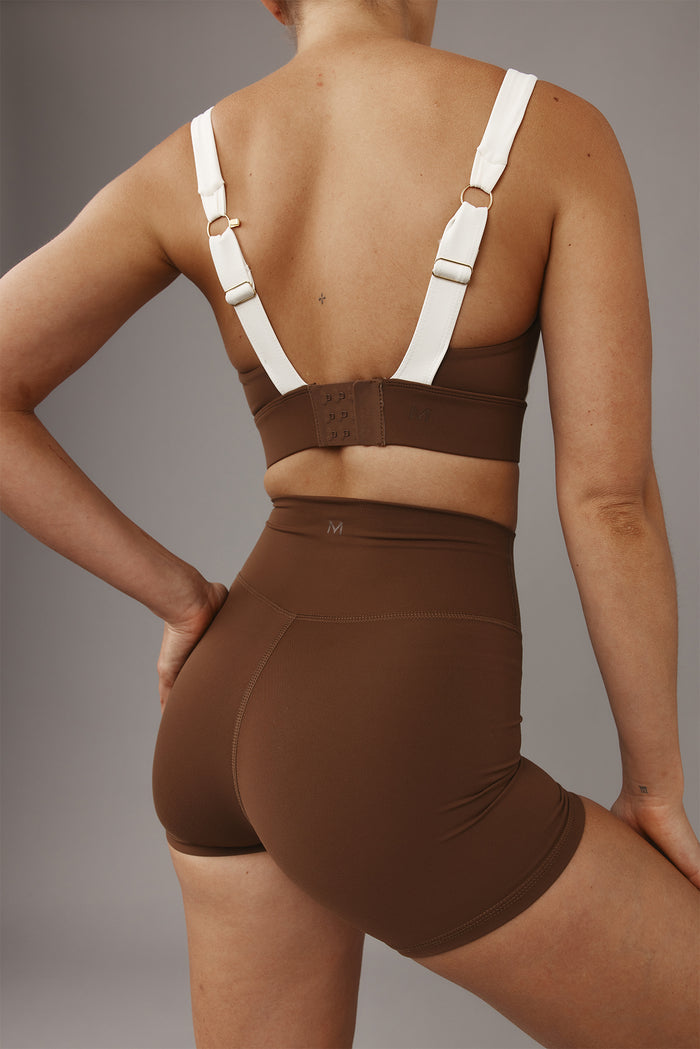 Rear view of Elysian Short 4.5-inch in Cliffside brown showcasing high-rise waistband and curve-enhancing fit on model against a gray studio background