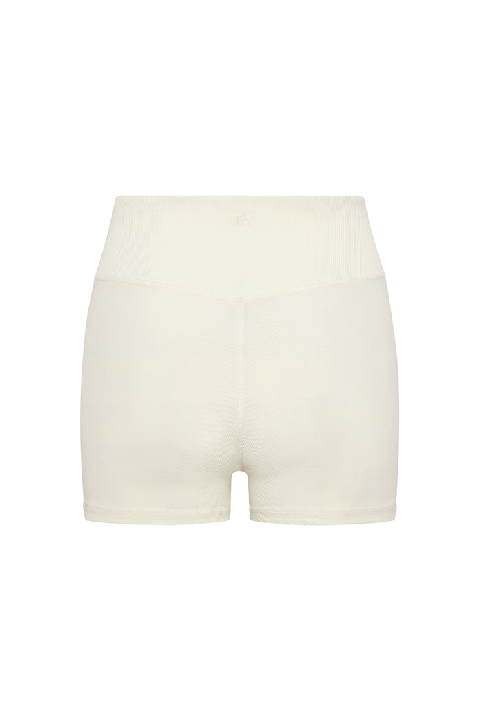 Cream ribbed high-waist seamless shorts with small embroidered "M" centered on the waistband.