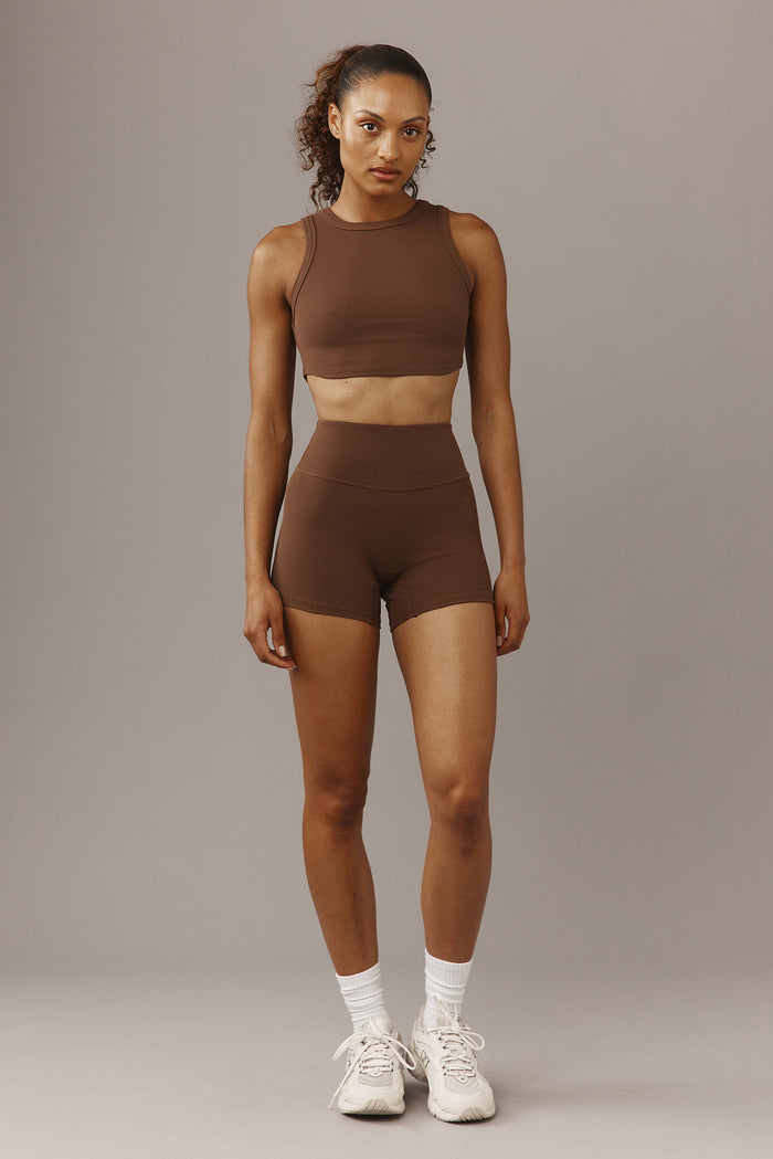 Front view of Elysian 4.5-inch Cliffside ribbed high-rise shorts on model with wide waistband against gray background