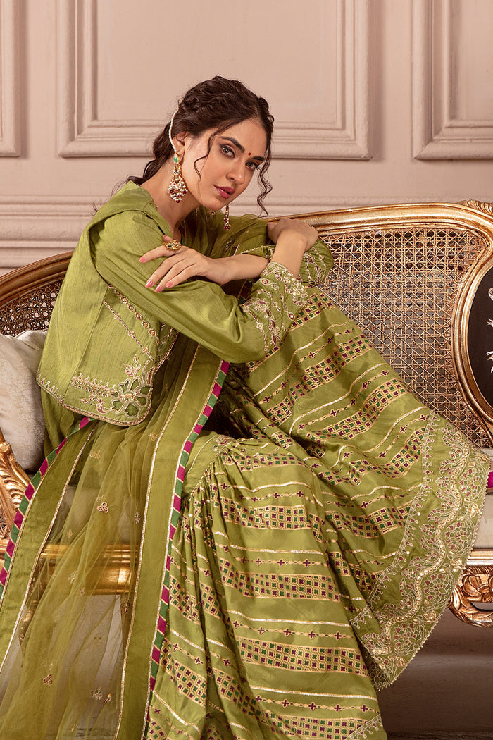 Seated pose of Eva green festive dress featuring detailed gharara borders and embroidered jacket work, ready to wear wedding gathering outfit.