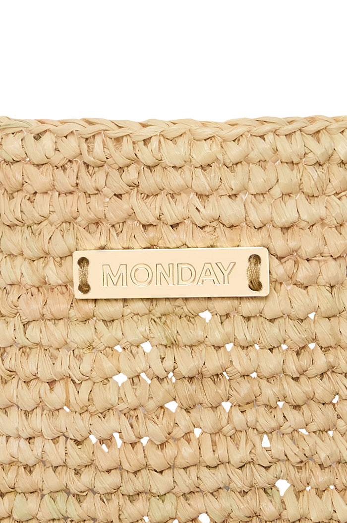Close-up of Exuma Bag - Natural showing braided raffia texture and gold MONDAY logo plaque on white background