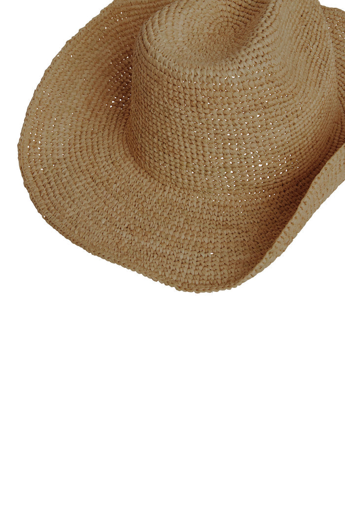Angled close-up of Exuma Raffia Hat in husk showing woven raffia texture and flexible wide brim on white background