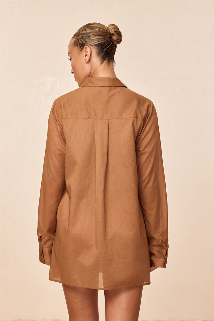 Back view of Fiji Tunic in caramel cotton voile showing center back pleat, long sleeves, relaxed fit, neutral background