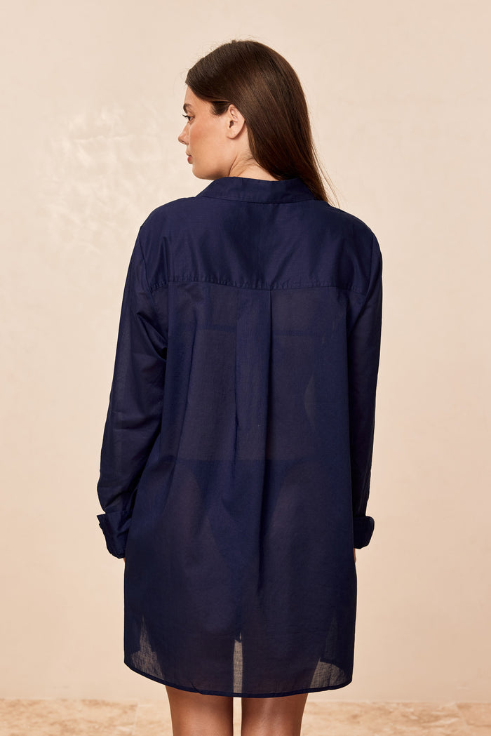 Back view of Fiji Tunic in Midnight Cotton Voile showing semi-sheer fabric, tunic length, and back pleat on beige background