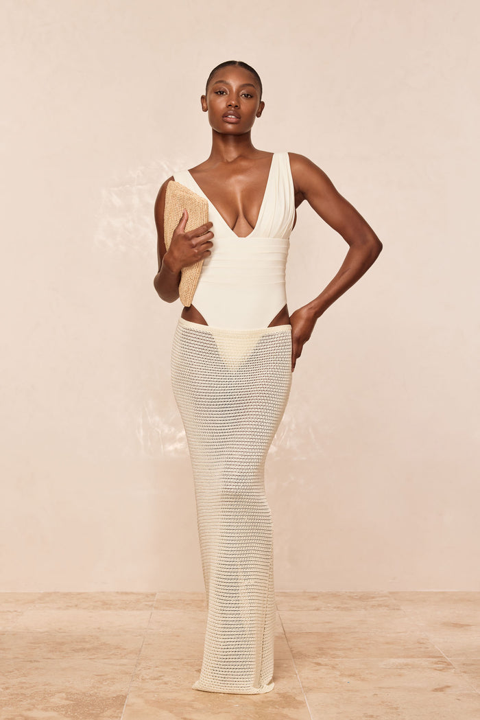 Front view of Fontelina Midi Skirt in ivory shiny treble knit, fitted semi-sheer crochet midi on model against neutral beige studio background