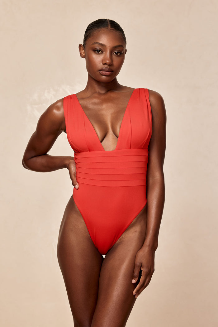 Front view of Florence one-piece in Chili Pepper with deep V-neck, pleated waist and cheeky fit against neutral background