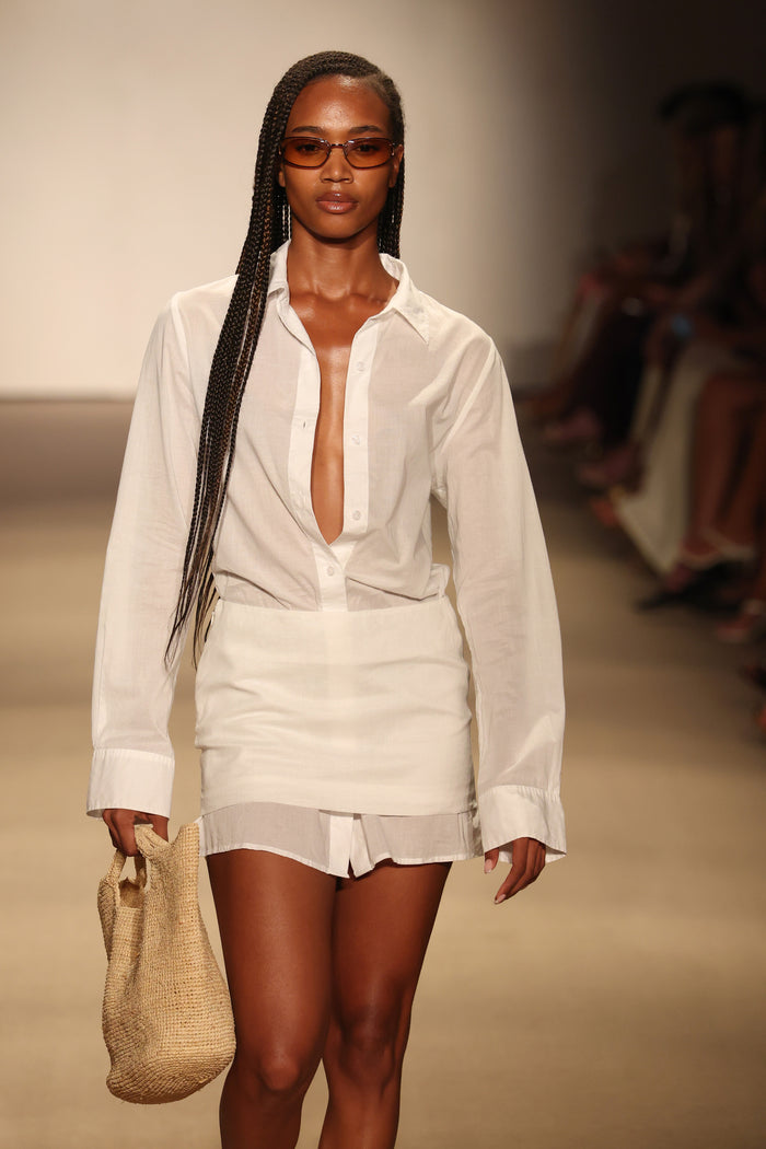 Front view of Fontelina Mini Skirt in white linen on model, mini length with high waist; styled with white shirt and woven tote