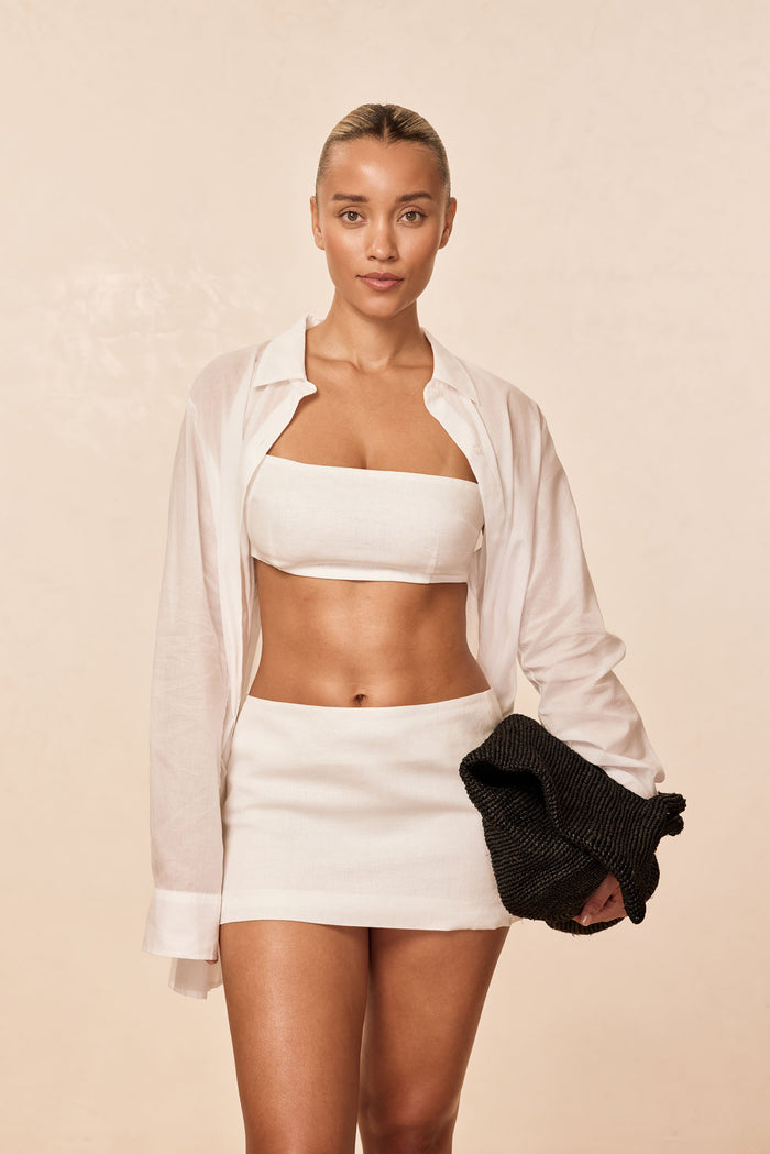 Front view of Fontelina mini skirt in white linen on model showing high-rise mini length against beige background