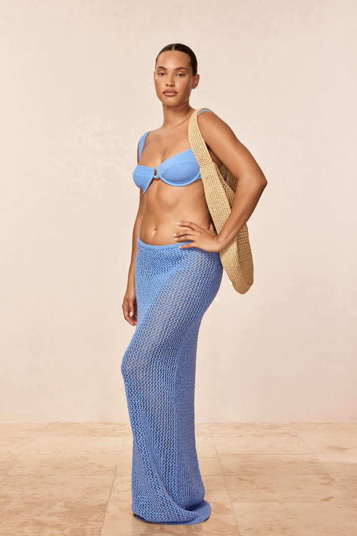 Right-side view of Fontelina skirt in azure petit crochet on model, sheer crochet knit, ankle-length slim fit, beige background