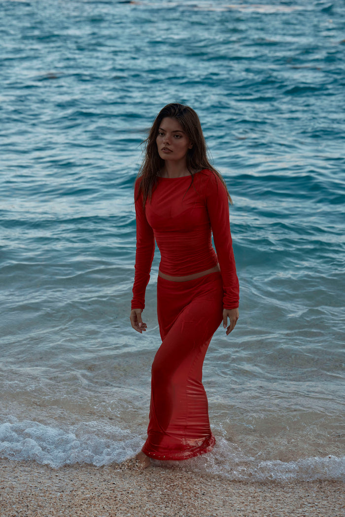 Front view of Fontelina Skirt in Chili Pepper mesh showcasing sheer ruched fabric and high-waist fit on a model at the shoreline