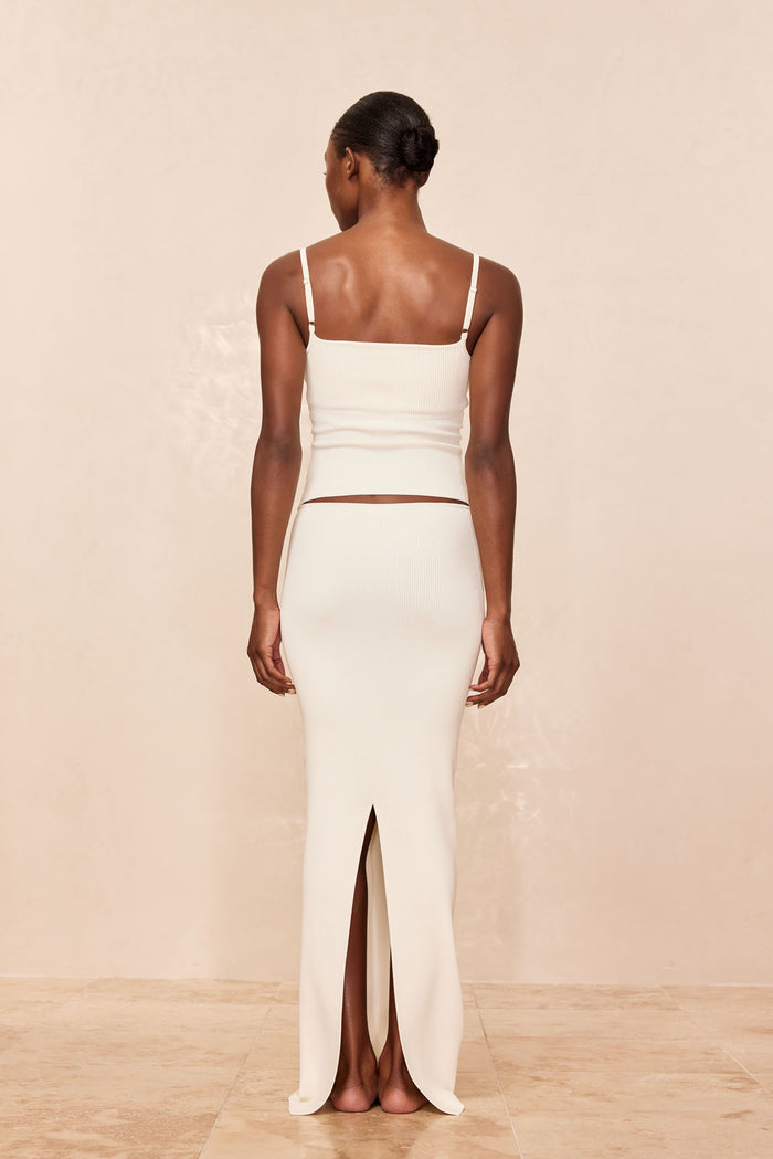 Back view of Fontelina Skirt in ivory rib knit with center back slit, paired with matching ribbed camisole on neutral background