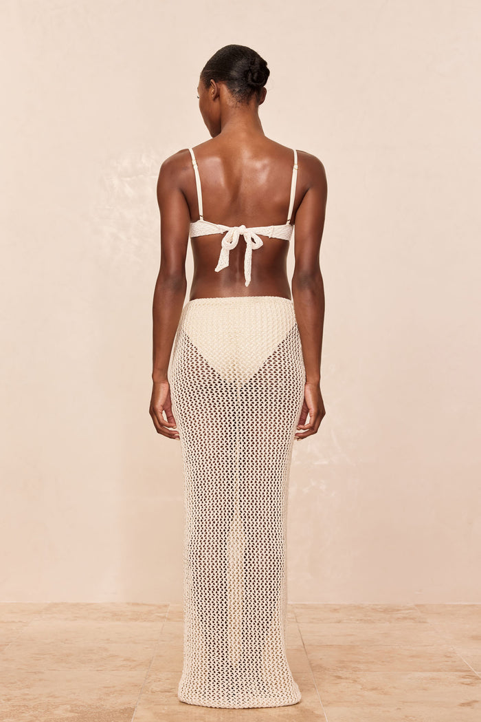 Back view of Fontelina Skirt in ivory petit crochet showing open-knit sheerness and high waist on neutral beige background