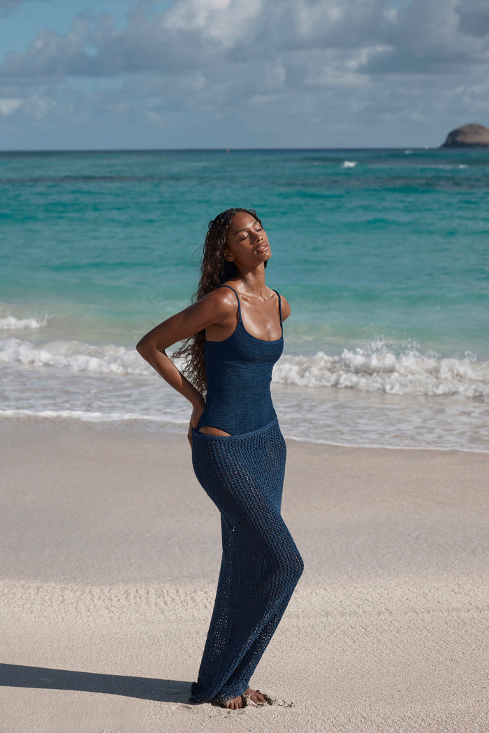 Side view of Bahamas One Piece in Midnight Crinkle on model showcasing scoop neckline, built-in bra, high-cut leg and textured crinkle fabric on a sandy beach