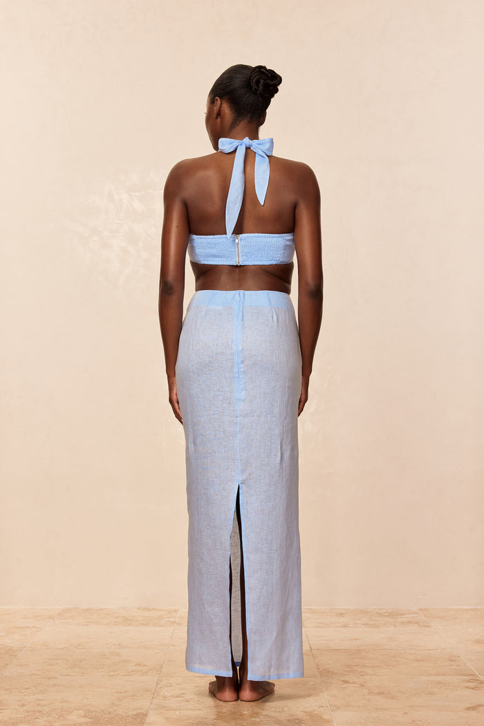 Back view of Fontelina Skirt in Sky Linen on model showcasing center back slit and high waist against beige studio background
