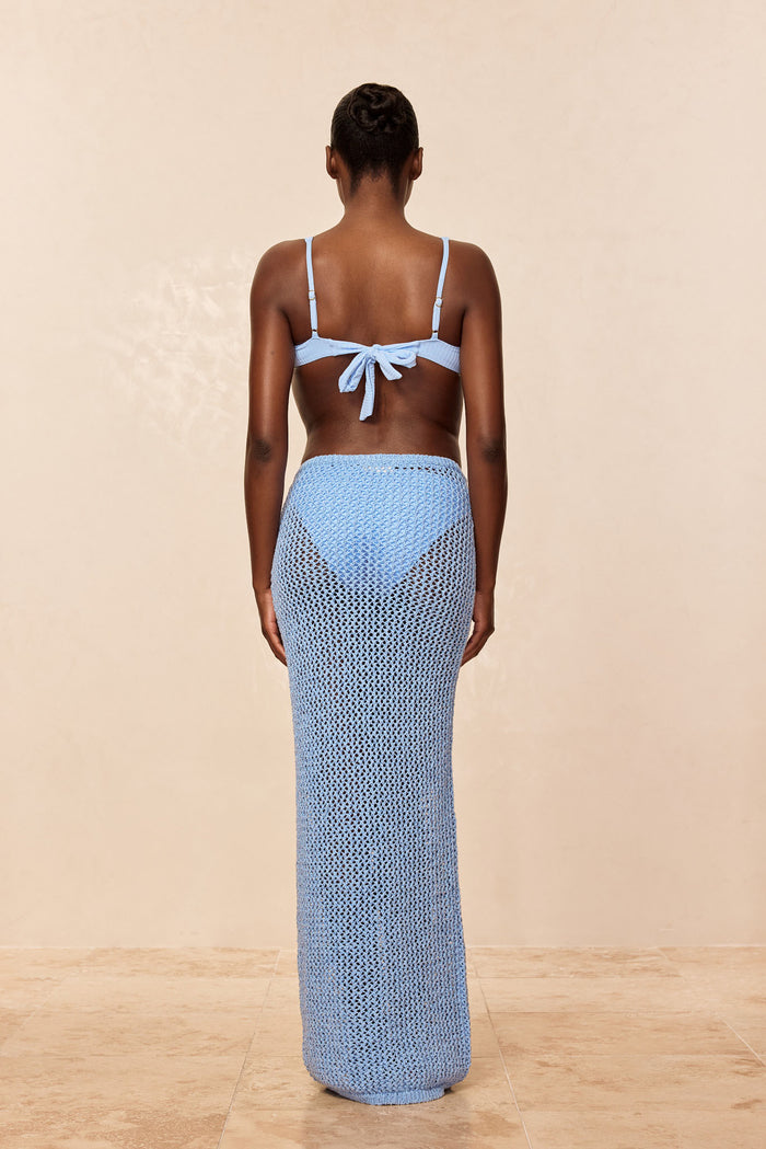Back view of Fontelina Skirt in Sky Petit Crochet showcasing full-length open-knit crochet mesh and fitted waistband with beige studio background