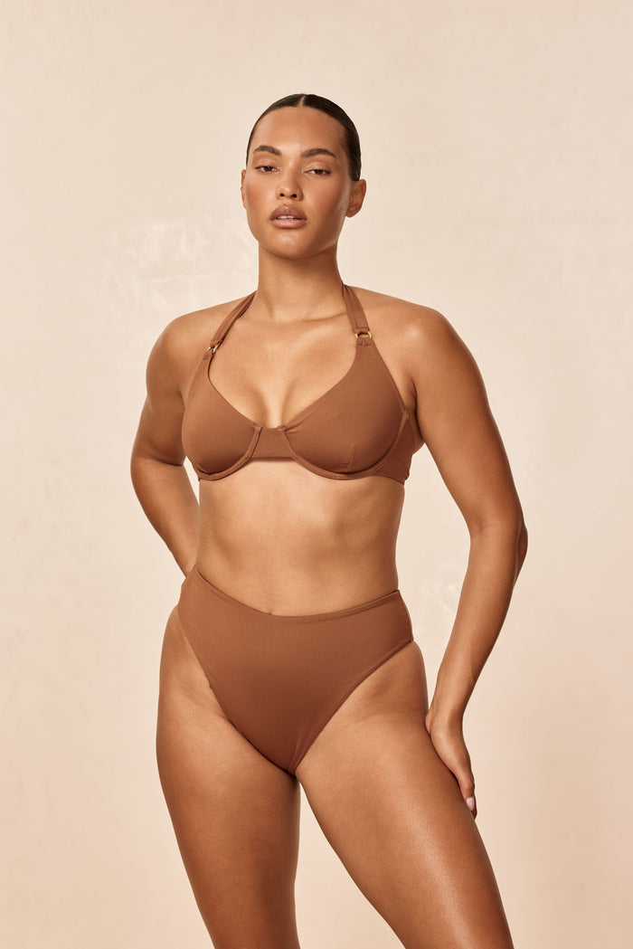 Front view of Formentera Bottom in Caramel showing high-waisted, high-leg cheeky coverage on model against beige background