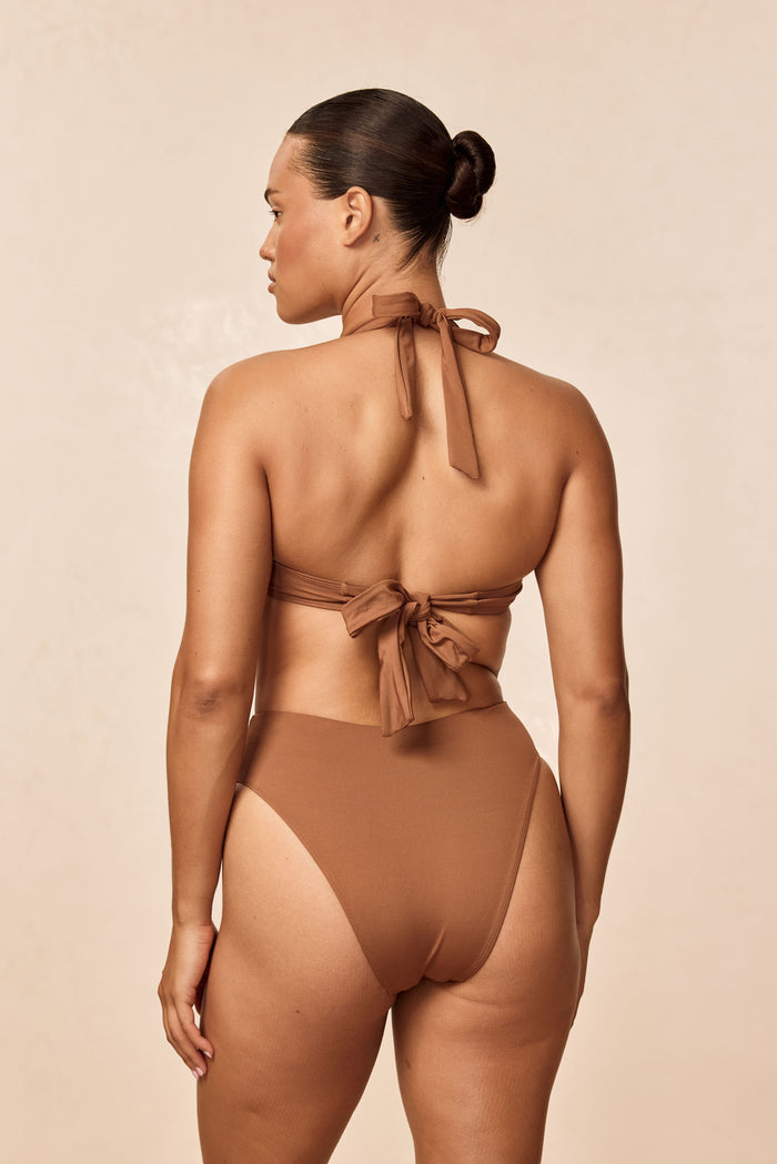 Back view of Formentera Bottom in Caramel showing high-waisted, high-leg cut and cheeky coverage on a model